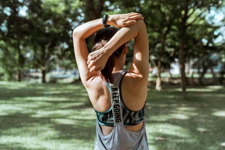 back of a woman stretching arm over head