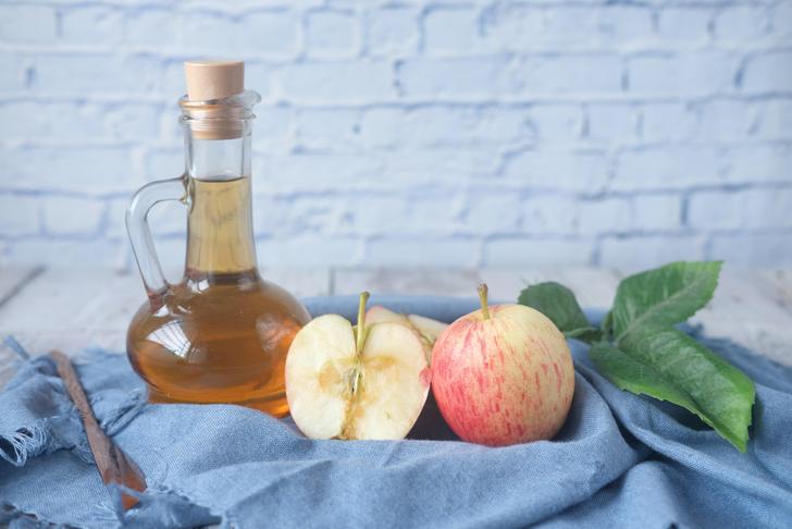 bottle of apple cider vinegar in a basket with apples