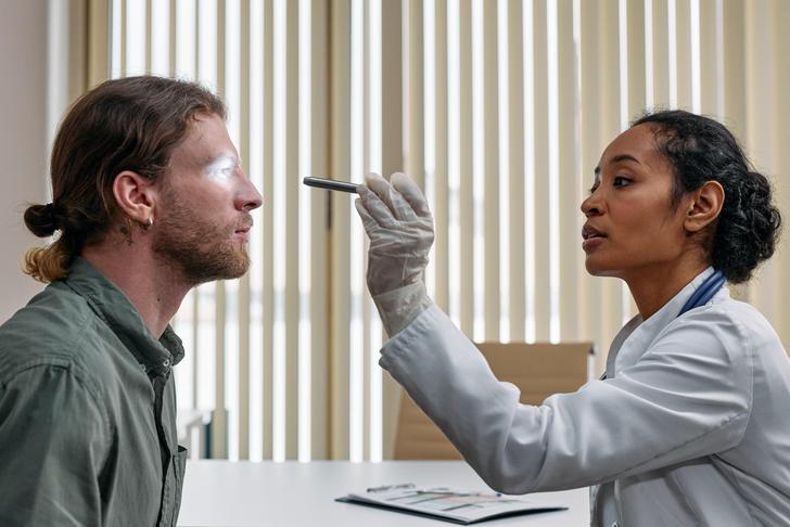 doctor checking man's eyes with light