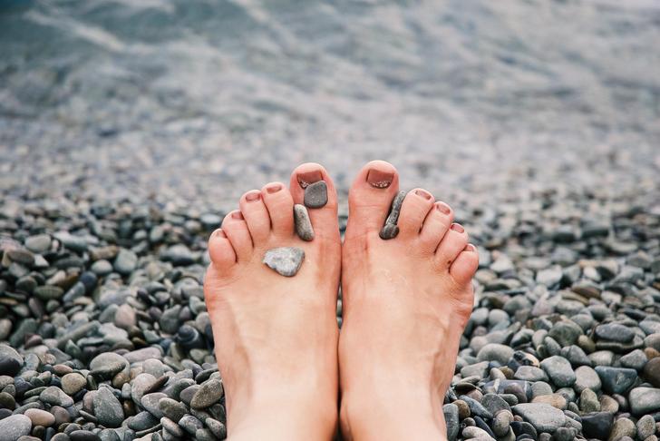 feet resting on rocks with rocks in between toes