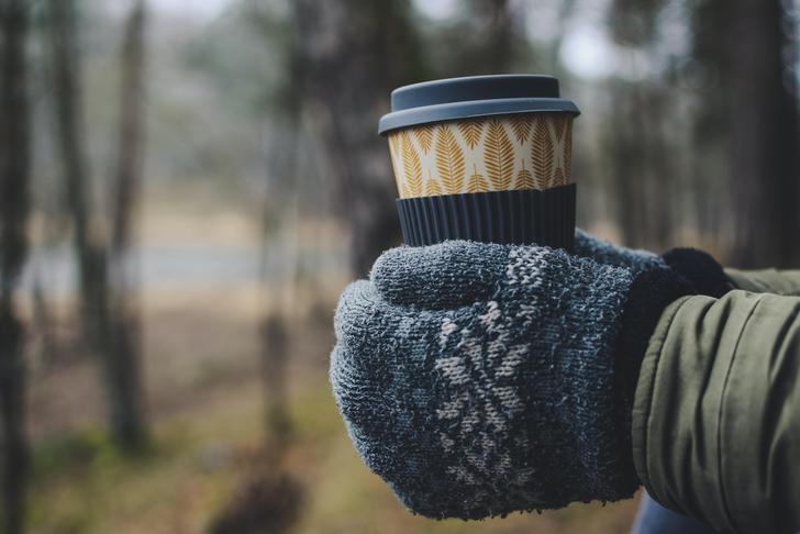 hands in gloves holding a coffee