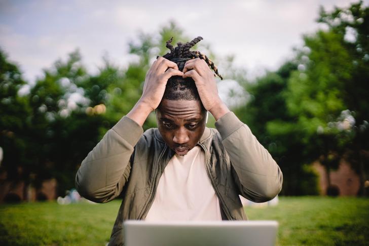 man holding head while looking at computer