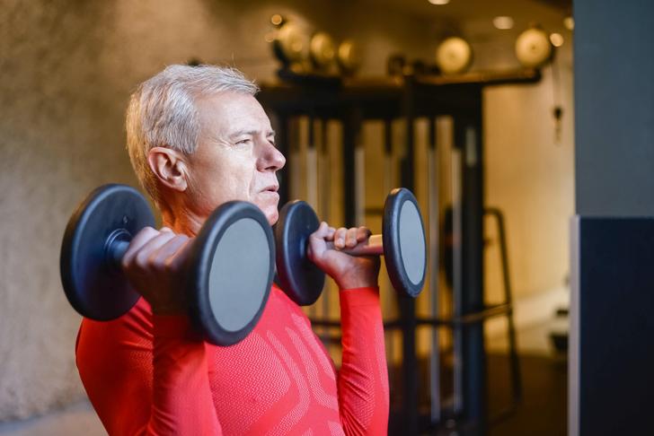 man lifting dumbbells over shoulders