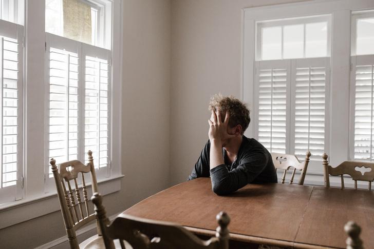 man sitting at table holding head