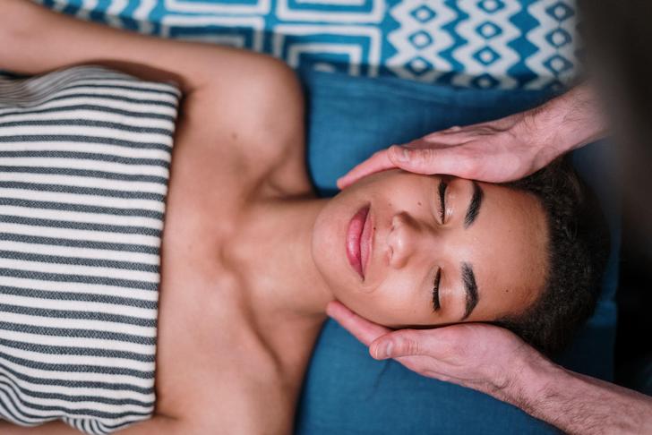 person laying down on their back receiving a face massage