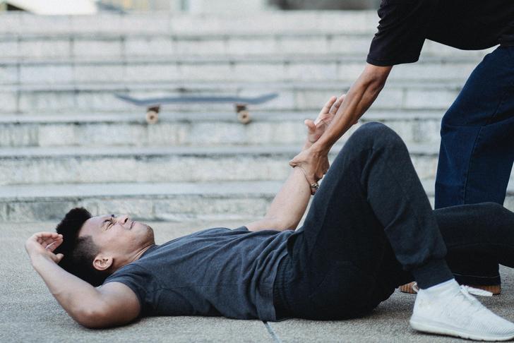 person laying on the ground injured with someone helping them up