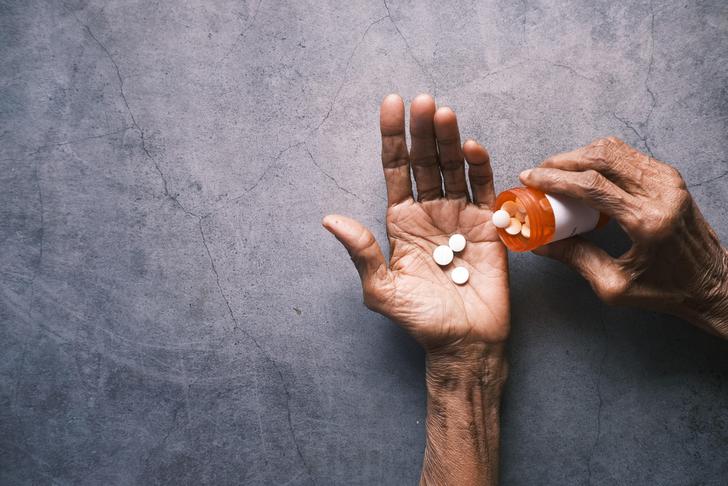 person pouring medication out of a bottle into hand