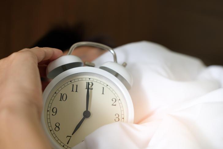 person resting in bed with clock