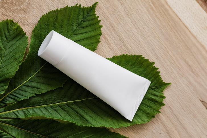 white tube on green leaves on a wooden surface