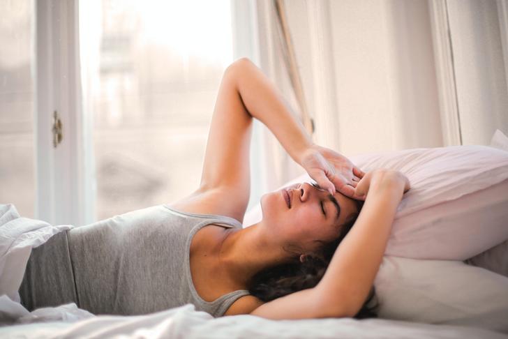 woman laying in bed holding her head