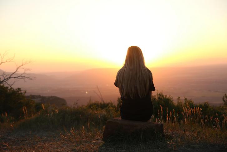 woman sitting on a tree stump staring at land